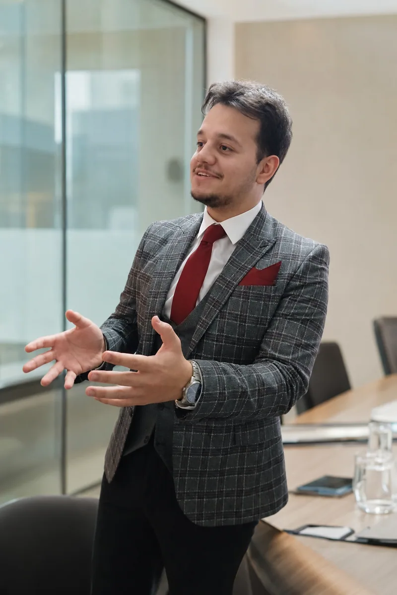 Omid Aslani Damirchi speaking in a grey suit